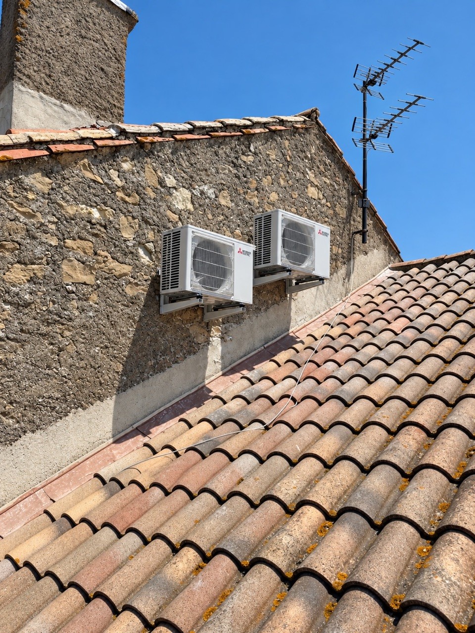 Deux groupes extérieurs posés sur une façade en pierre